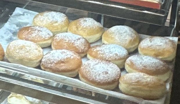 O tavă cu gogoși pudrate cu zahăr în vitrină