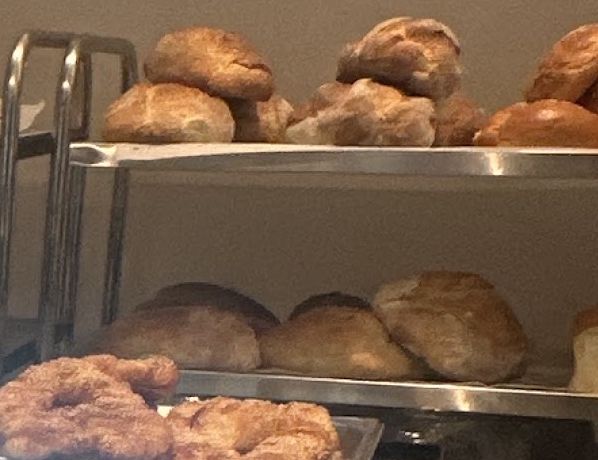 Pâini rotunde, rumene, pe rafturile din spatele tejghelei