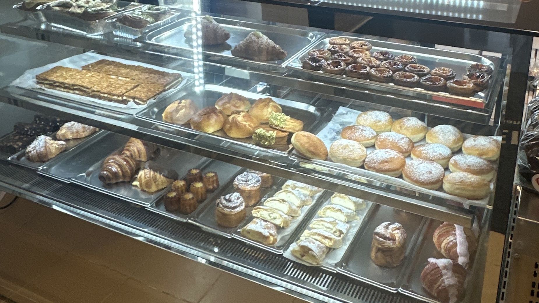 Vitrina luminată Chocolatine&Co, cu tăvi de croissante, gogoși, ștrudel și prăjituri